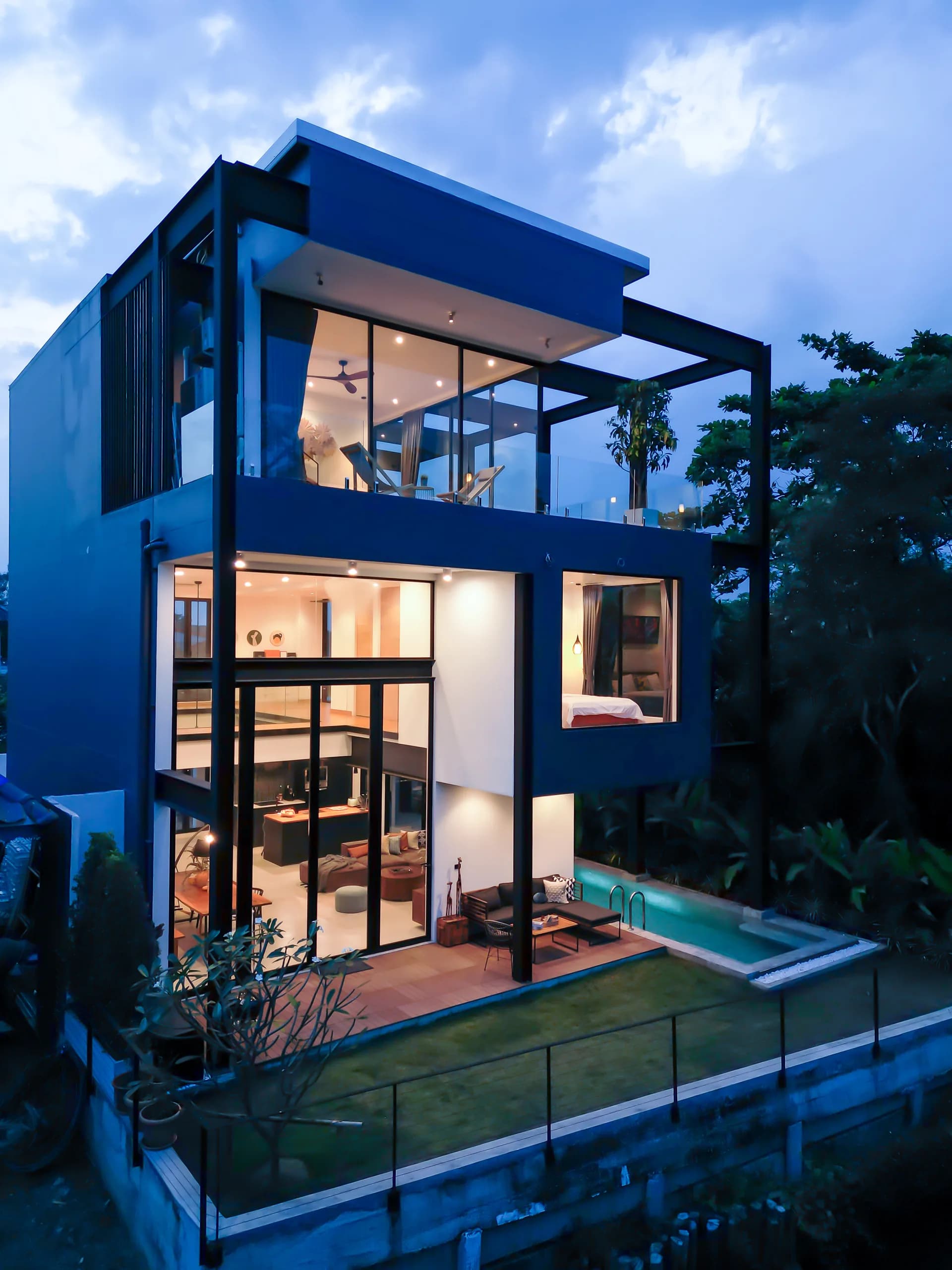 Steel House, three-storey black steel exterior at twilight with private pool